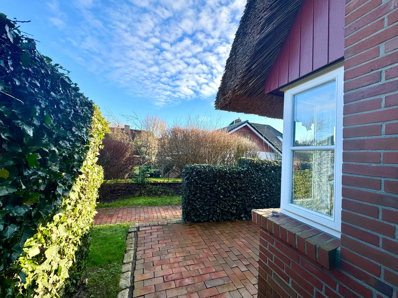 Backstein-Pflasterweg und Hecke seitlich am Pastoratshof