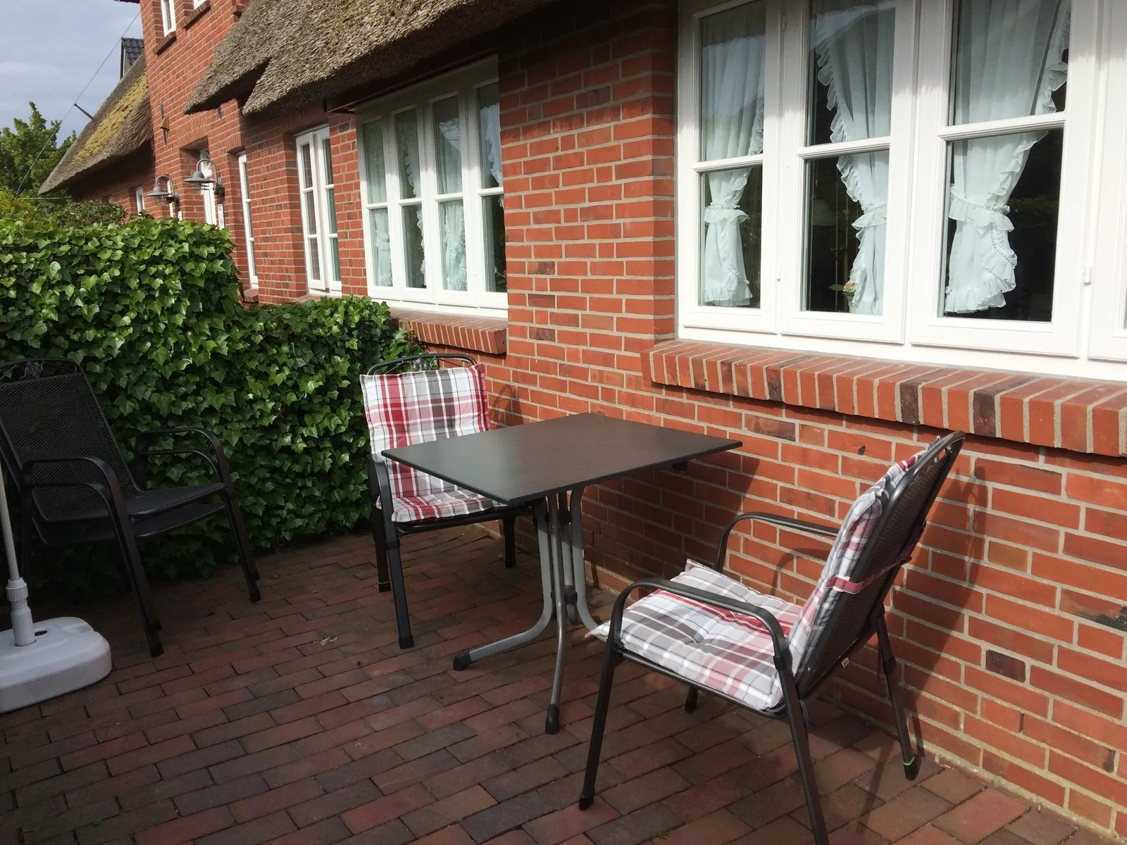 Terrasse mit Tisch und zwei Stühlen vor den Fenstern der Ferienwohnung